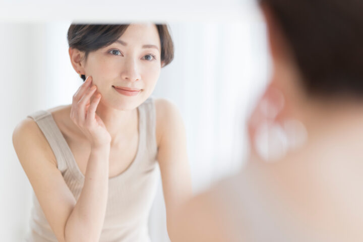 鏡を見ながら頬を触っている女性